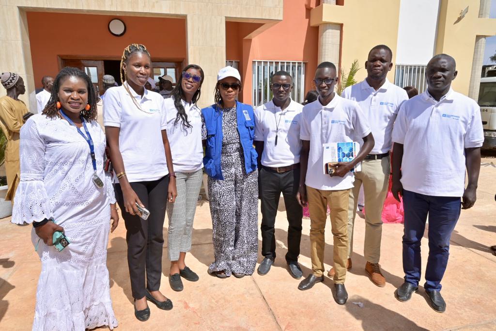 Groupes de Jeunes garçons et de jeunes filles, entourant une femme portant un gilet avec logo bleu