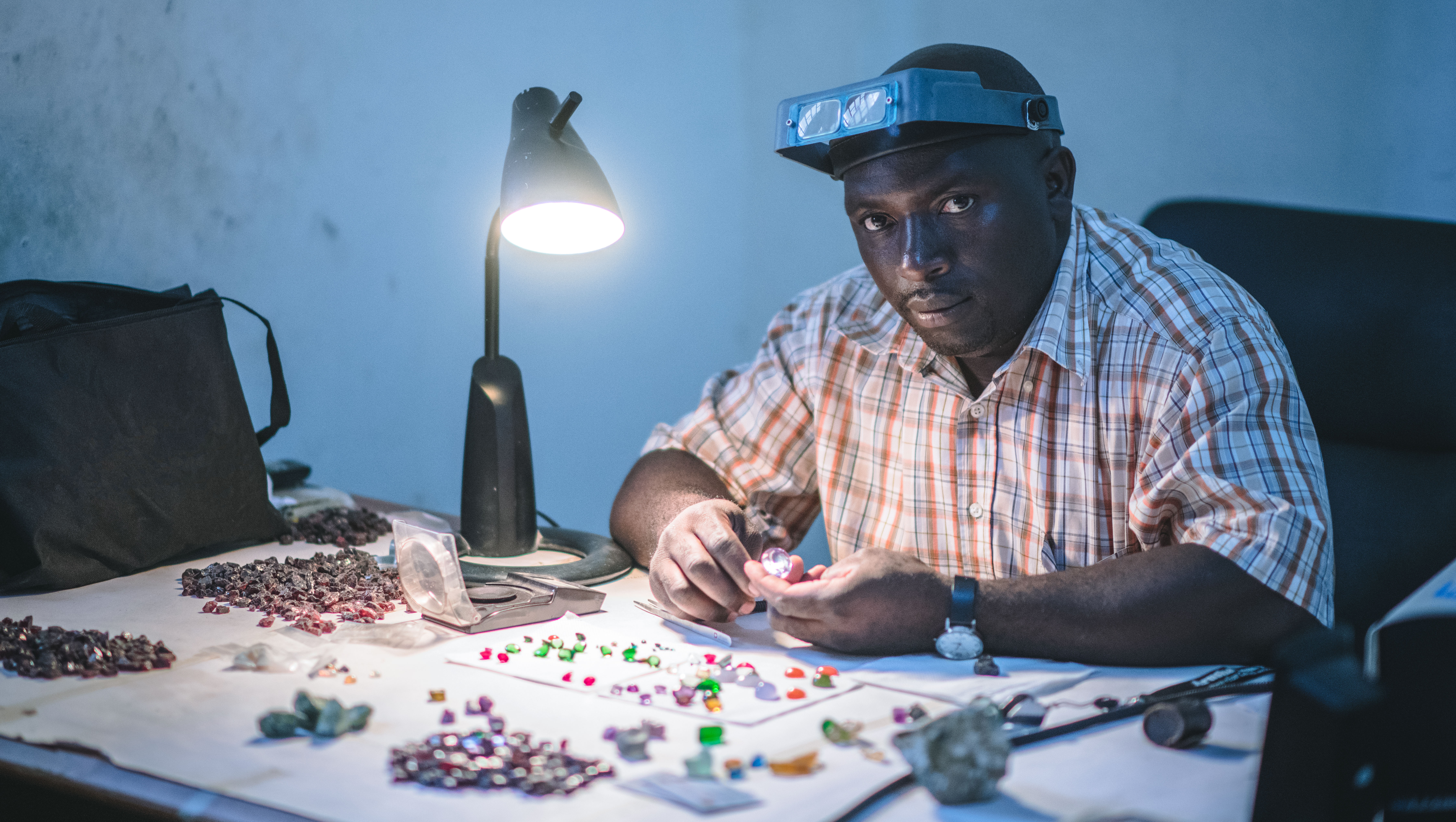 a man sitting at a table examining unprocessed gems