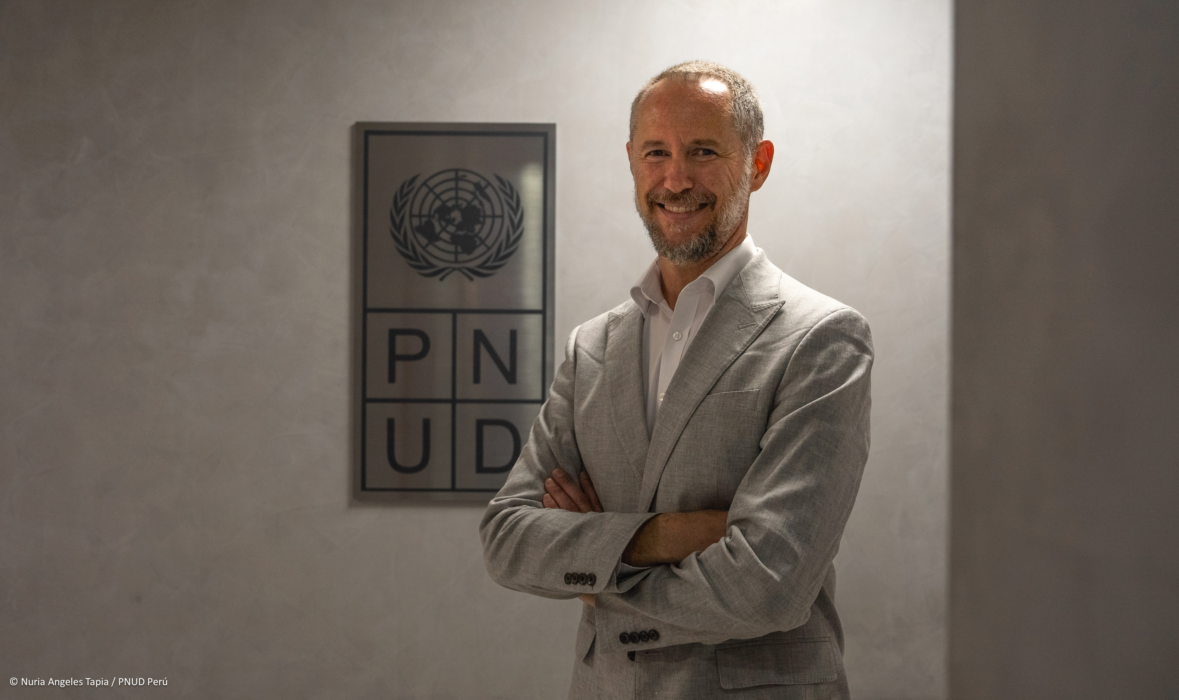 Un hombre con traje y corbata, Luis da Silva, frente al escudo del PNUD