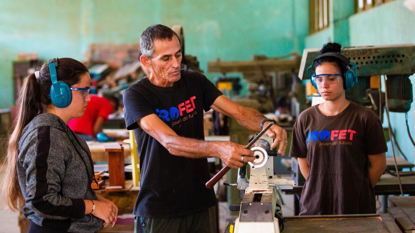 Profesor de la enseñanza técnica profesional dando clases a dos alumnas en el aula especializada de carpintería. Centro politécnico de la `rovincia Pinar del Río.