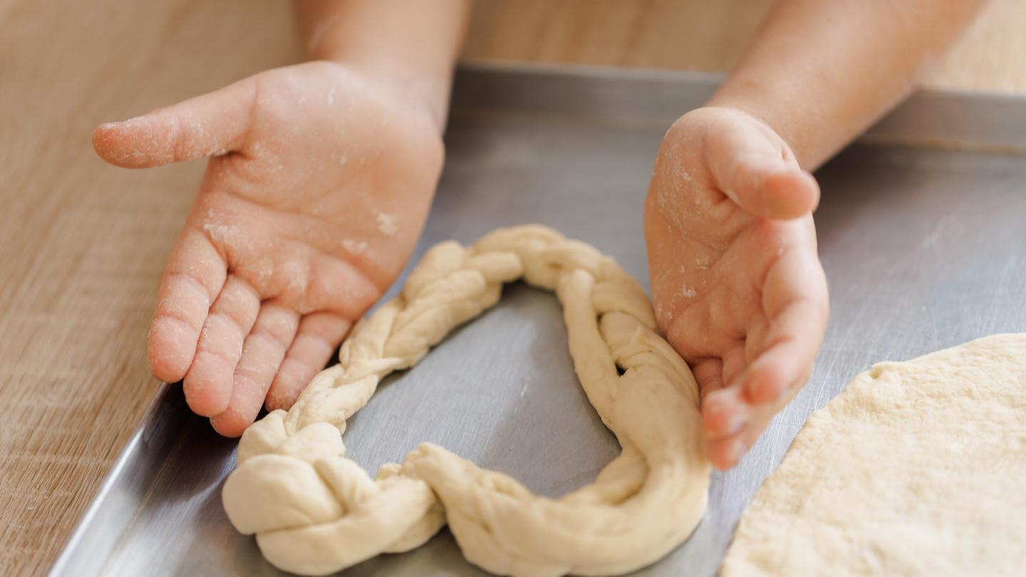 a hand holding a piece of bread on a cutting board