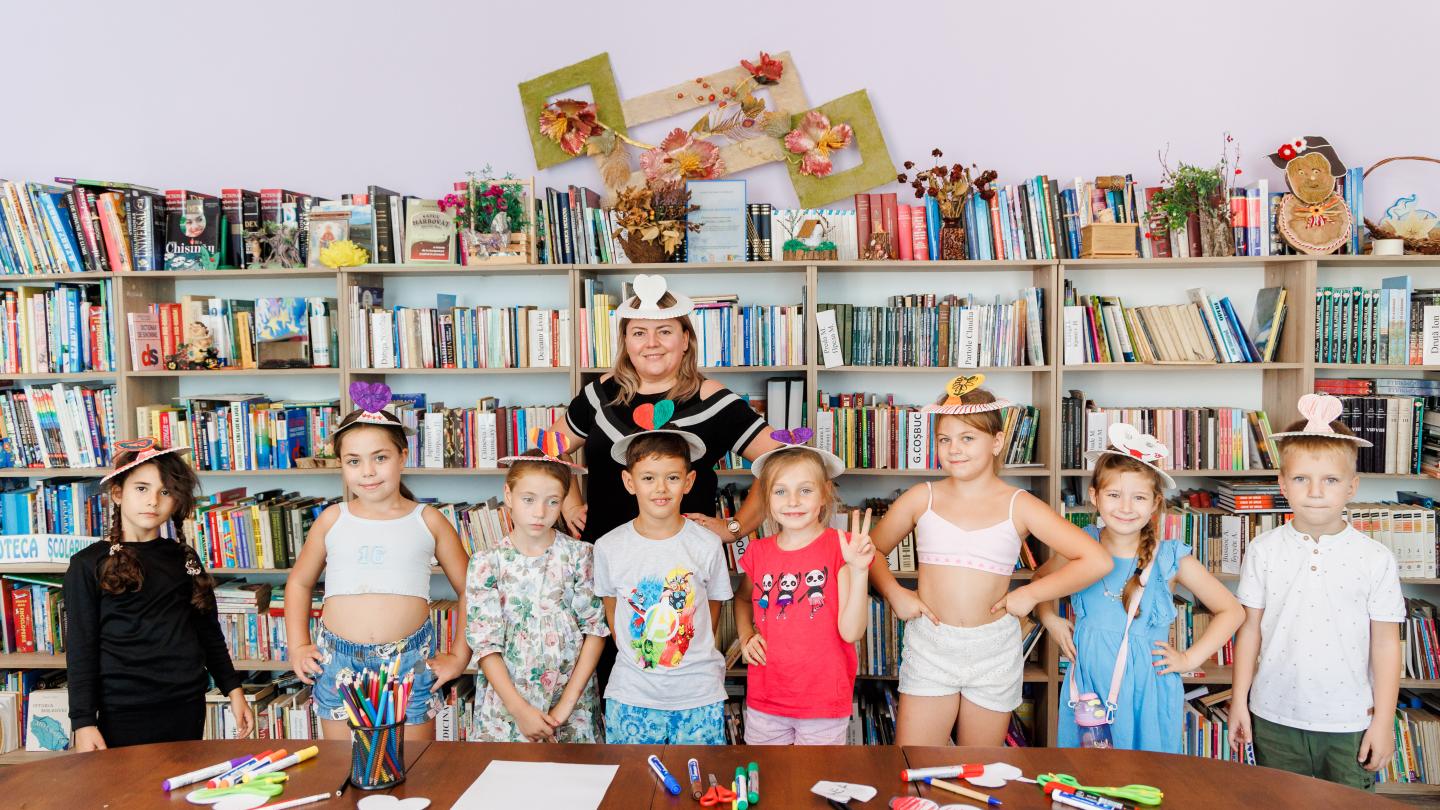 a group of people sitting at a table with a book shelf